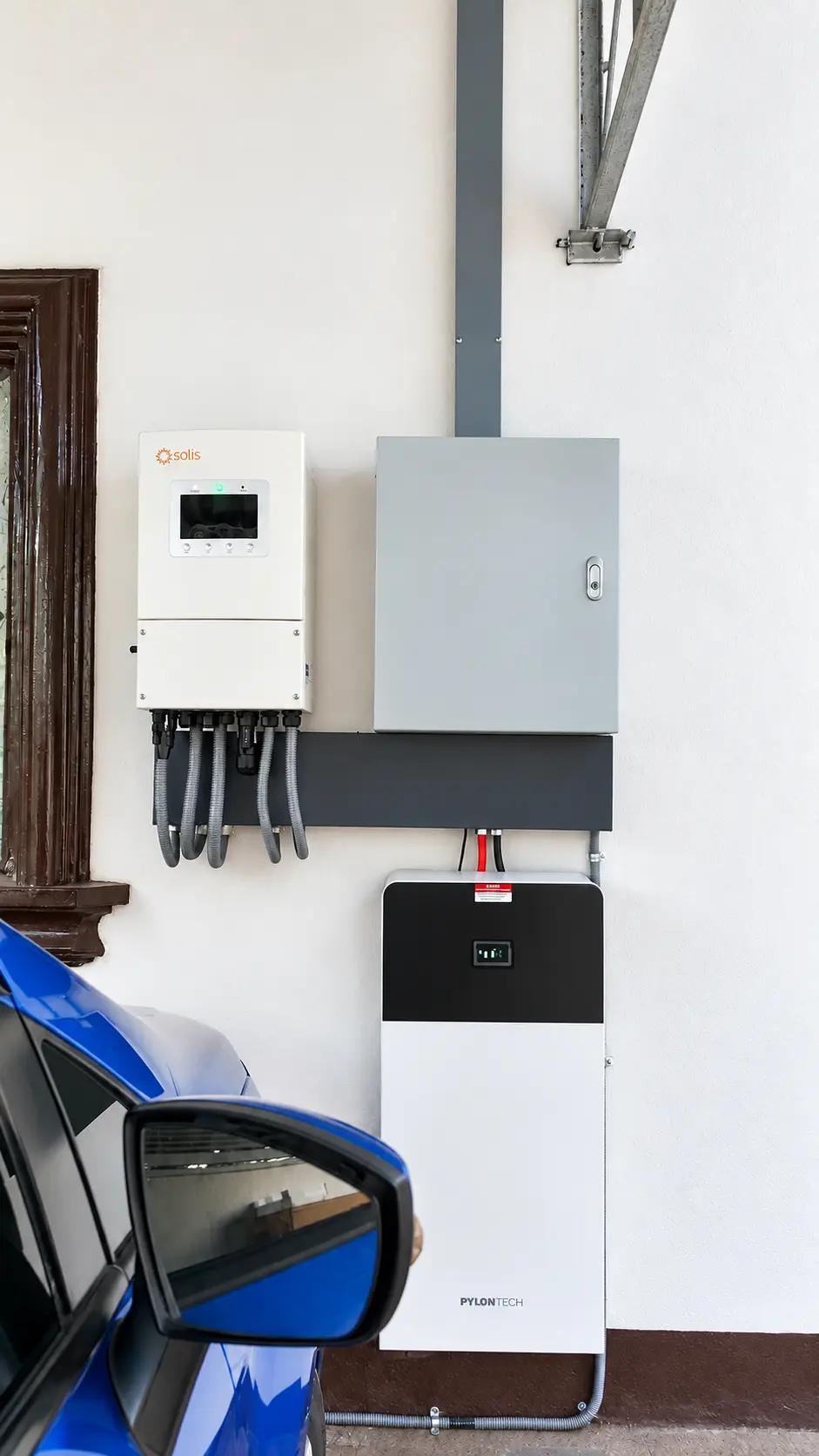 Hybrid inverter, electrical enclosure and battery installed near a blue car in Las Piñas